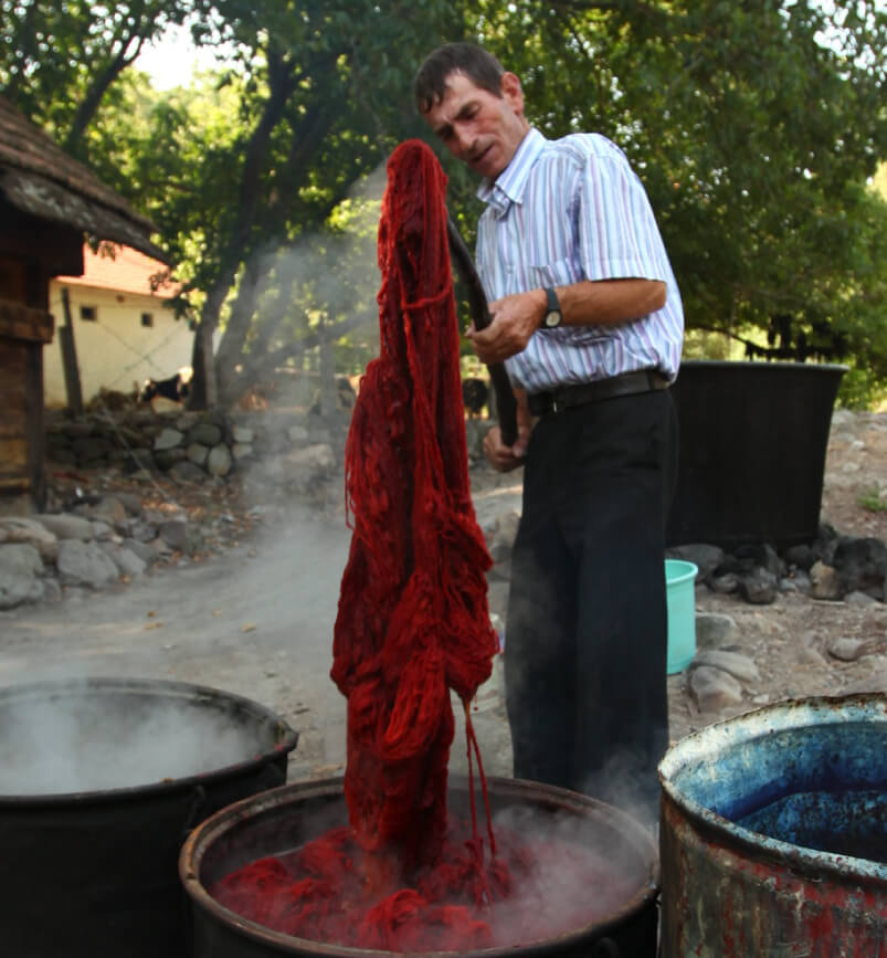 天然染料で糸を染め上げる織り手の男性の写真