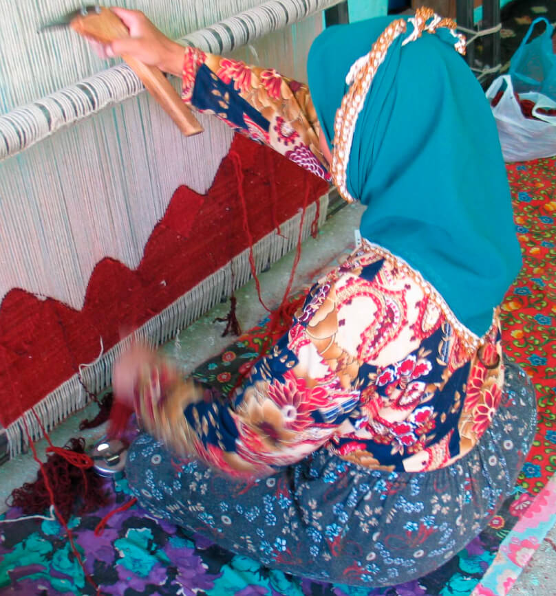 キリムを織る女性の後ろ姿の写真