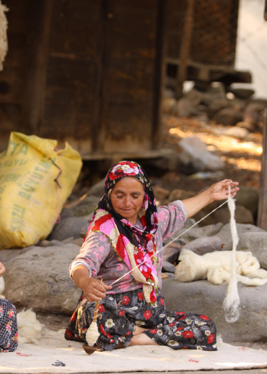 糸を手紡ぎしている女性の写真
