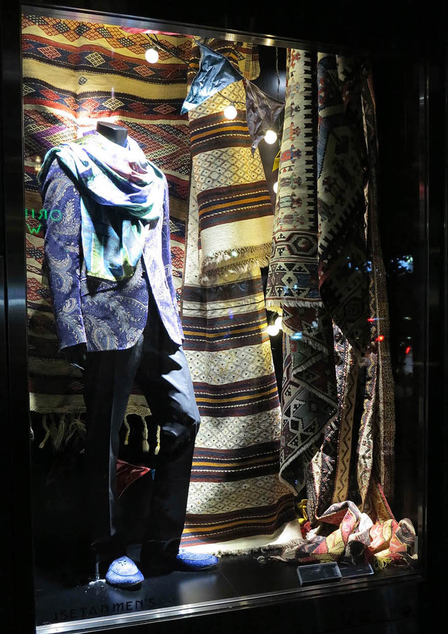 ウィンドウに展示されるブラウン系のキリムと服の写真