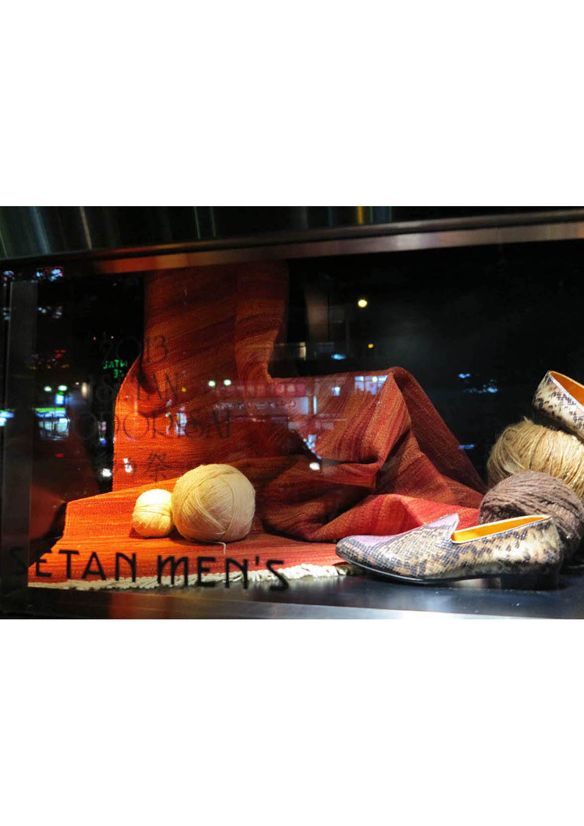 ウィンドウに展示される赤いキリムと靴の写真